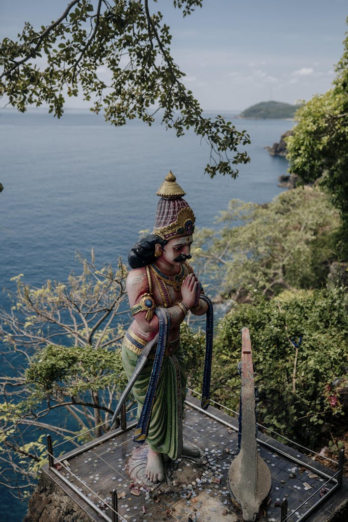 Colorful Hindu deity statue with lush greenery and ocean view in Trincomalee, Sri Lanka.